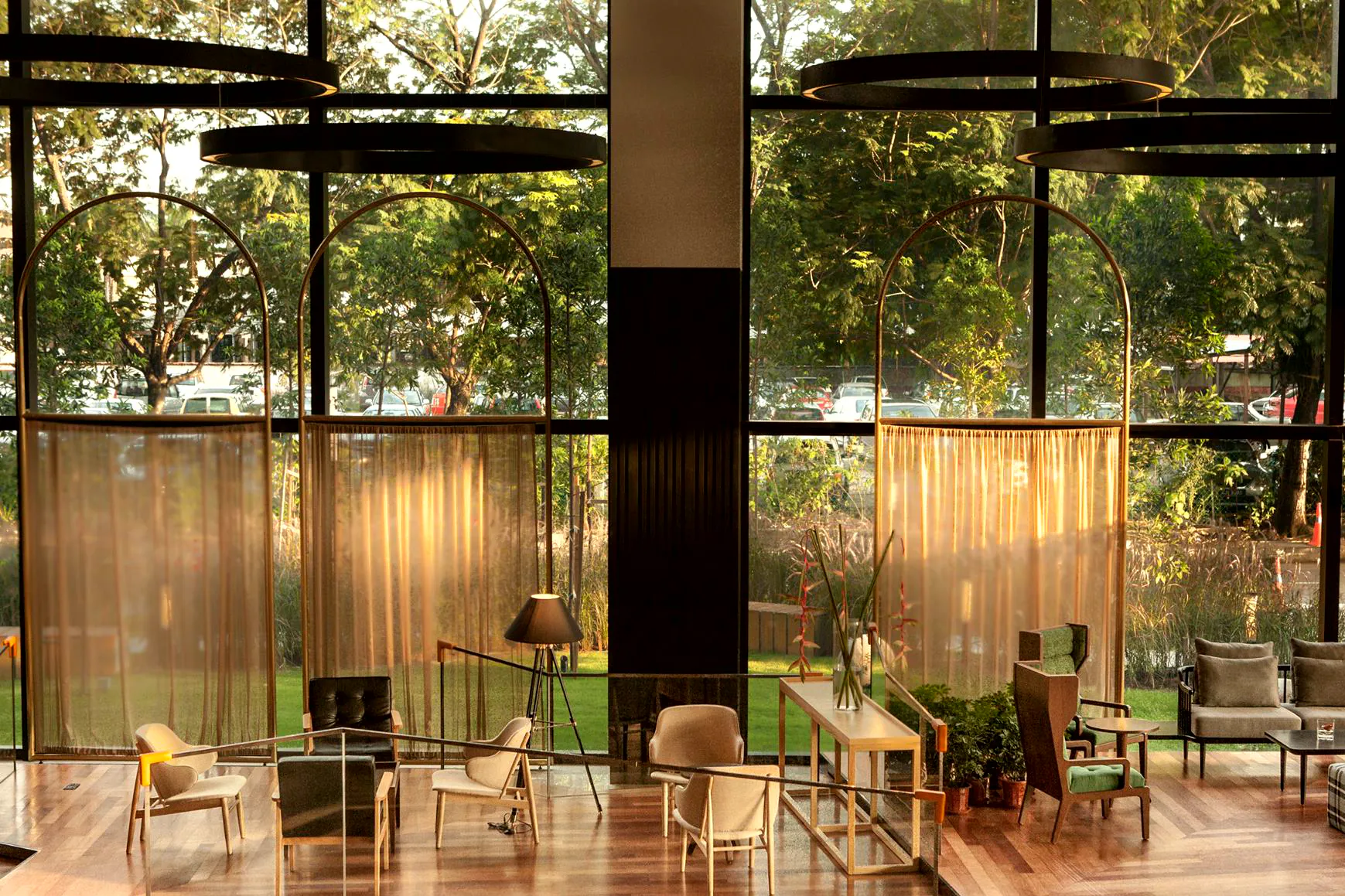 Glass garden lounge with timber floors and lush planting outside at Weil Hotel